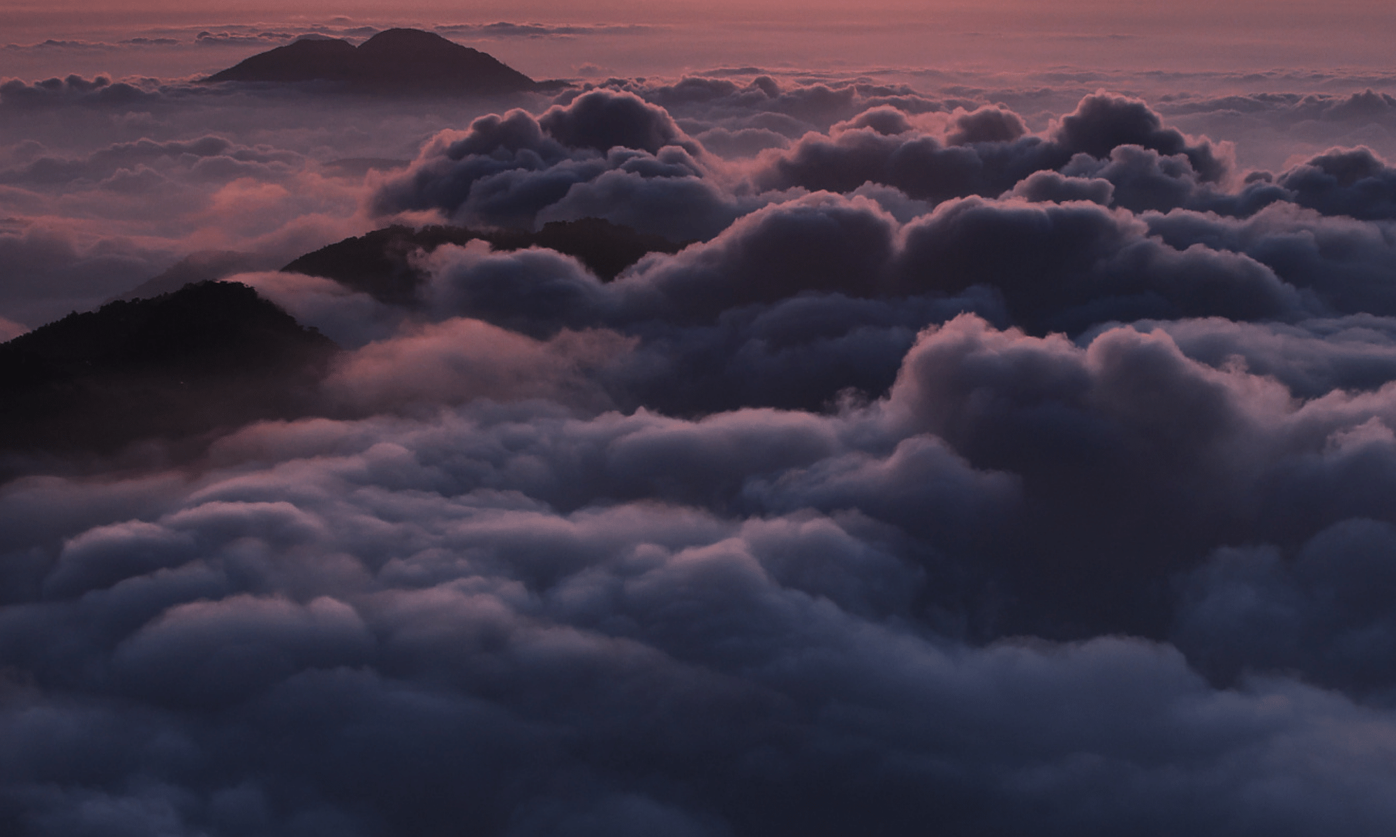 clouds touching the tips of the mountains, shades of purple as if sunset is setting